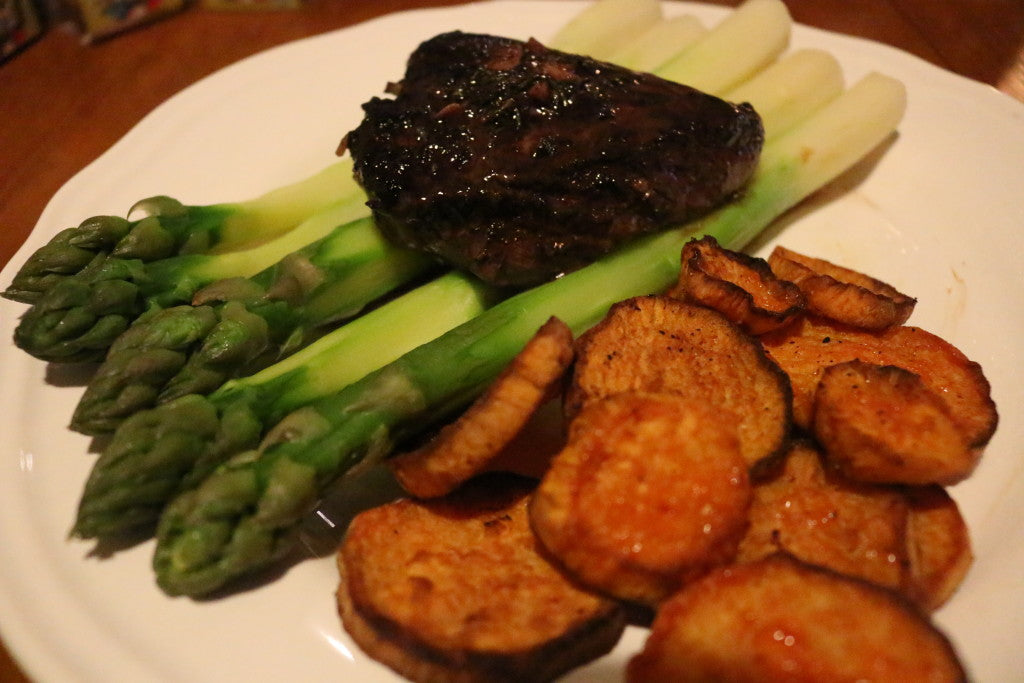 Zartes Rindersteak mit einer kräftigen Rotweinsauce, knuspriger Süßkartoffel und frischem grünem Spargel
