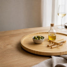 Bamboe draaiplateau met olijven, olijfolie en soepstengels op een eiken tafel