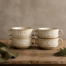 Vier crème Soup soepkommen gestapeld in twee stapels op een eiken tafel