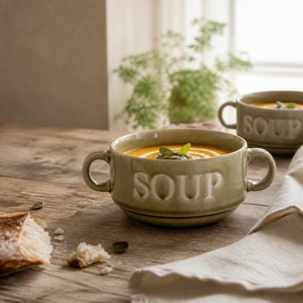 Groene soepkom Soup met pompoensoep op een houten tafel bij het raam