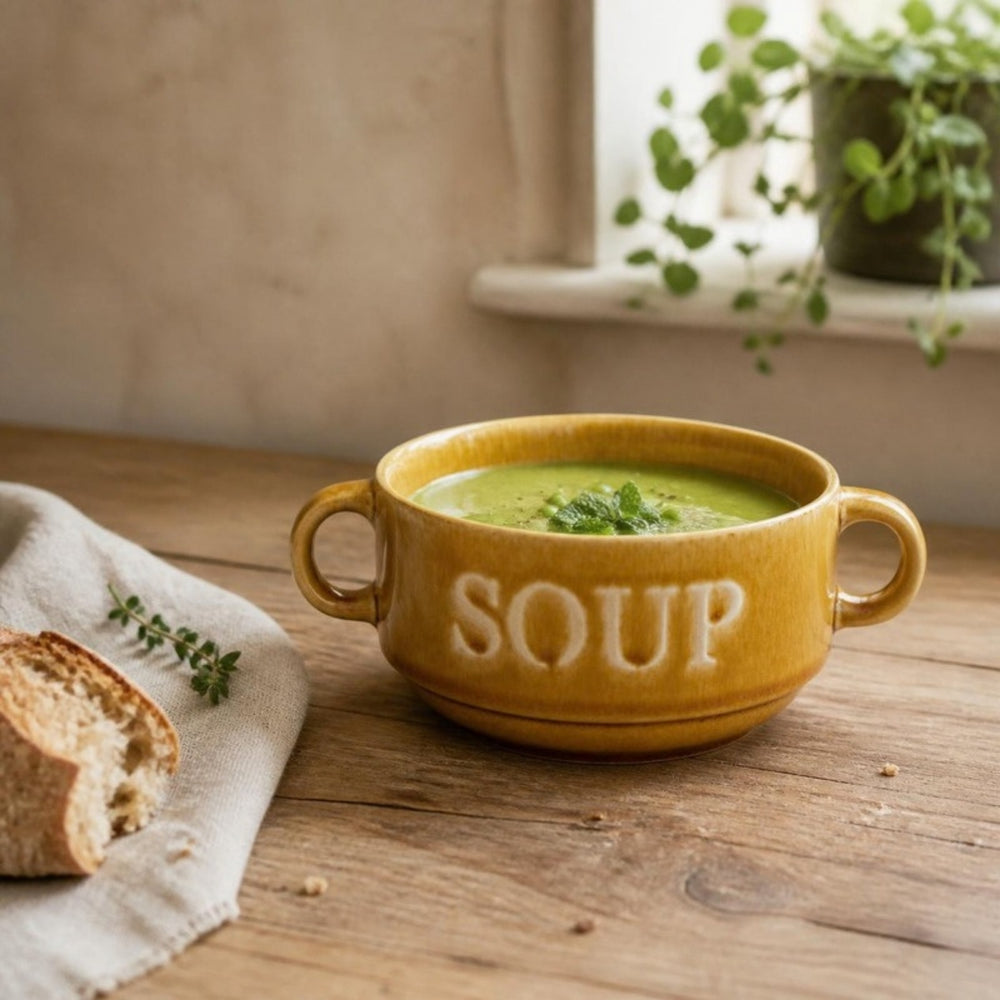 Okergele soepkom Soup met erwtensoep op een houten tafel bij het raam