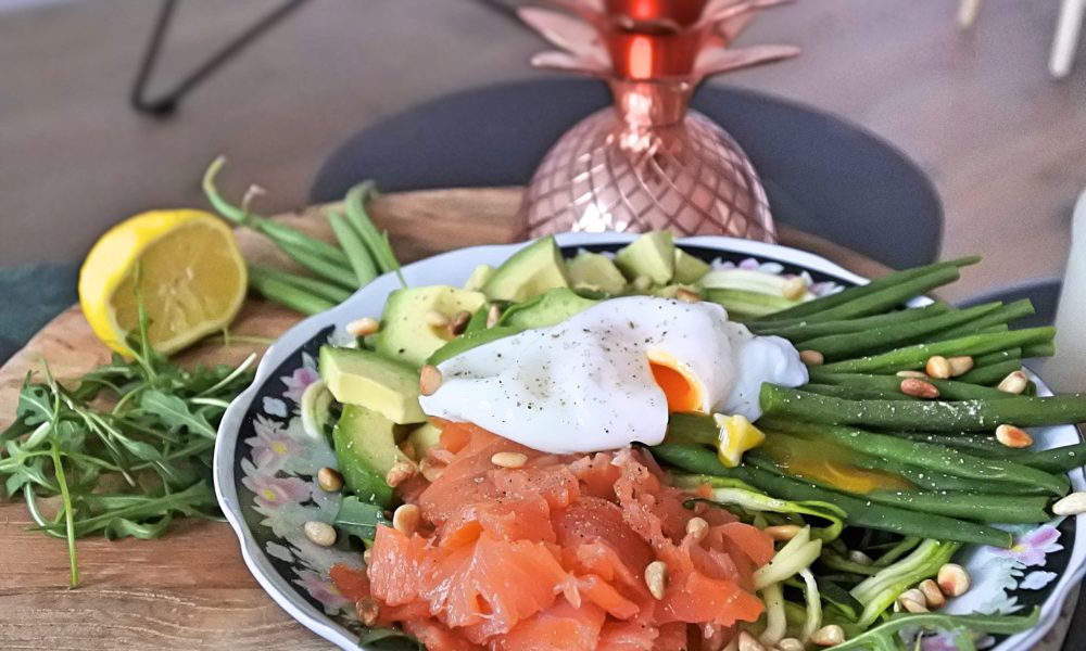 Eine frische und nahrhafte Bowl mit Zucchinistreifen, geräuchertem Lachs und einem pochierten Ei