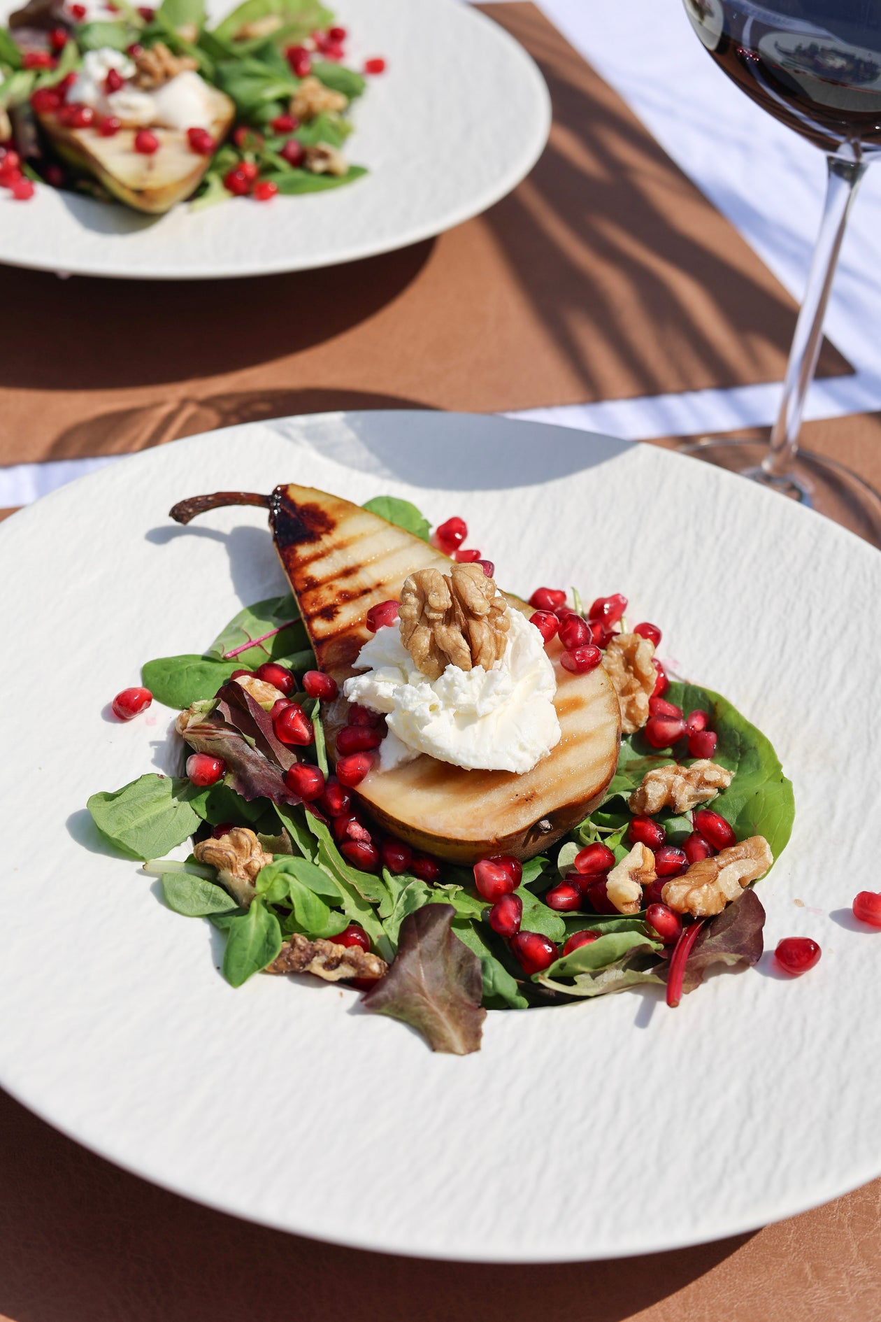 Warme, gegrillte Birne auf einem Bett aus Salat, mit cremiger Mascarpone, knusprigen Walnüssen und frischen Granatapfelkernen.