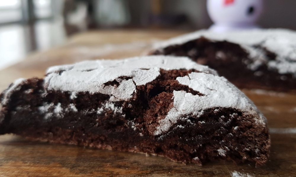 Ein großer, fudgy Schokoladenkeks mit einer schneeweißen Schicht Puderzucker