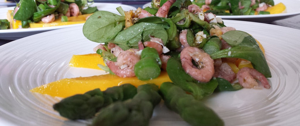 Ein frischer Frühlingssalat mit grünem Spargel, Garnelen und Mango